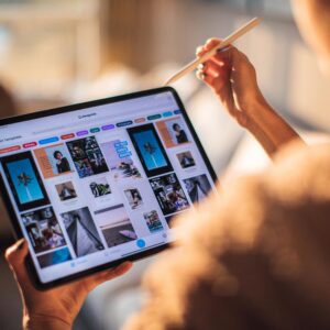A person uses a digital tablet with a stylus indoors in a warm, cozy setting.